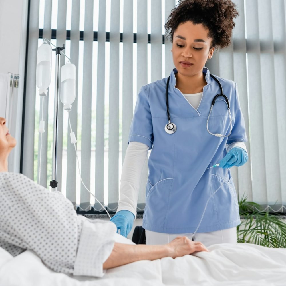 African american nurse holding catheter near elderly patient in clinic